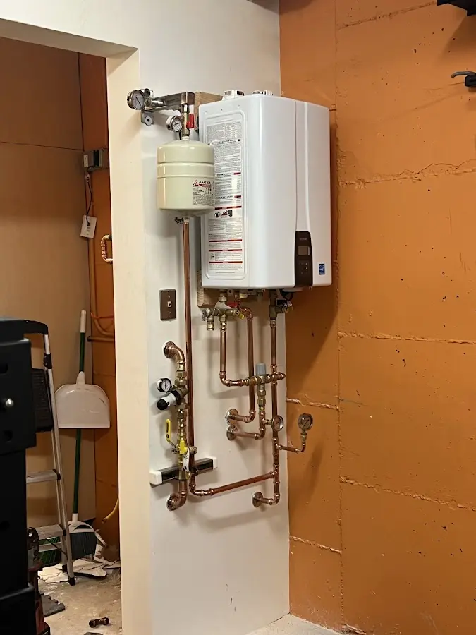 Plumbing technician inspecting water heater connections in Plum
